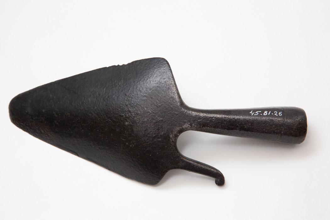 Outil en fer forgé, en forme de petite pelle pointue avec un crochet à droite. Le manche est manquant.