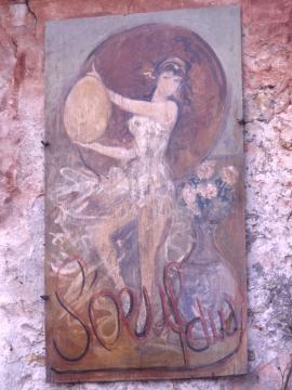 Enseigne peinte de l'Auberge de l'Œuf Dur : une danseuse vêtue d'une robe vaporeuse tient devant elle un grand œuf