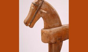 Avant-main d'un cheval à bascule en bois, des deux côtés de la tête se trouve une poignée. Les yeux sont en relief et leur tour est peint en blanc, le filet rudimentaire a été réalisé en cuir.