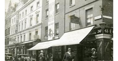 Vue de Londres, datée de 1934 : une rue animée avec voitures et personnages. Photographie rapportée de Londres par Pierre Mac Orlan à l'occasion d'un de ses reportages.