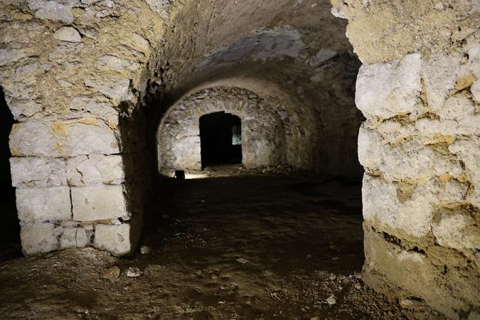 Photographie couleur de la cave du château de Doue ; c'est une cave voutée en pierres de taille de couleur claire 